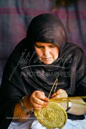 Image du Maroc Professionnelle de  Sous sous une tente bédouine une artisane prépare un sous plat en osier durant le grand Moussem de Tan Tan, classé en 2005 patrimoine immatériel humain mondial de l'Unesco. Le Moussem est une sorte de foire annuelle, à la fois économique, culturelle et sociale. chaque année la majorité des tribus et des grandes familles nomades du désert se retrouvent sur un site désertique "Place de la Tolérance et de la Paix " à la périphérie de Tan Tan où  danse, chants, course de chameaux et fantasia font partie des festivités. , Samedi 18 septembre 2004, ((Photo / Abdeljalil Bounhar)